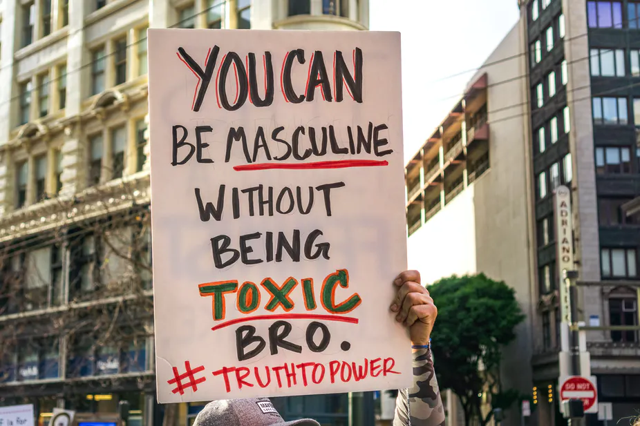 Protest sign reading "You can be masculine without being toxic bro. #TruthToPower"
