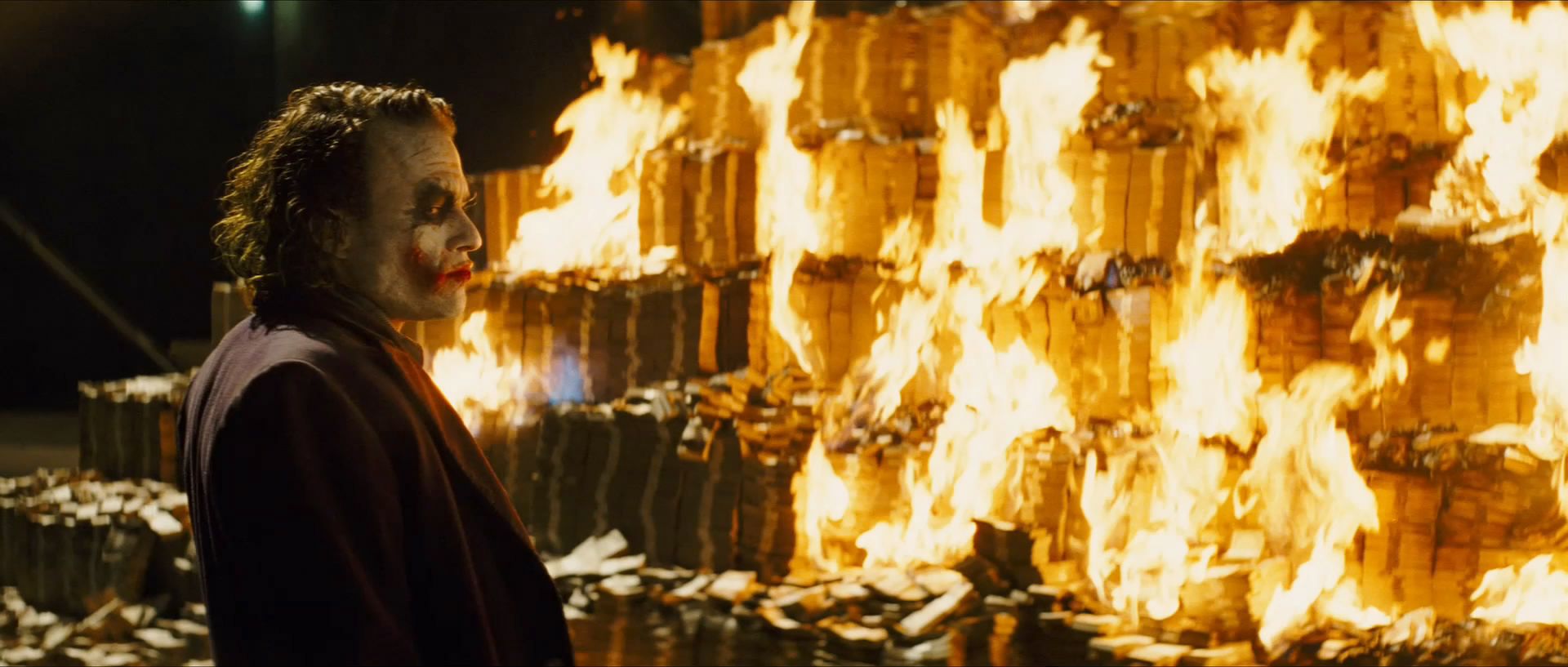 The Joker from The Dark Knight watching a huge pile of money burn
